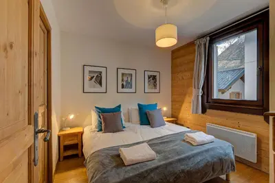 a bedroom with a large bed with blue pillows at Apartment le Paradis 1 - Alpes Travel - Central Chamonix (sleeps 4) in Chamonix-Mont-Blanc