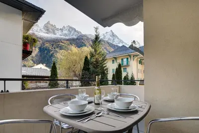 a table with chairs and a bottle of wine on a balcony at Apartment le Paradis 1 - Alpes Travel - Central Chamonix (sleeps 4) in Chamonix-Mont-Blanc