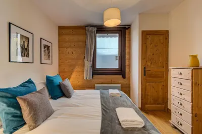 a bedroom with a bed with blue pillows and a window at Apartment le Paradis 1 - Alpes Travel - Central Chamonix (sleeps 4) in Chamonix-Mont-Blanc