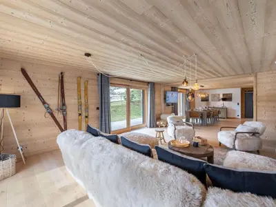 a living room with a large couch and skis at Appartement neuf spacieux à Megève avec jardin privatif - FR-1-569-60 in Megève