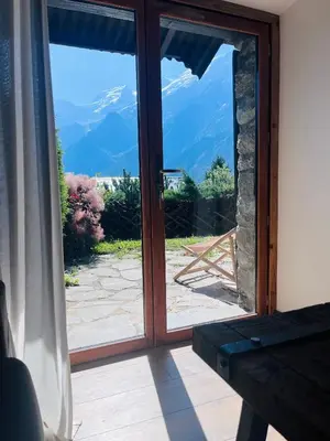 a sliding glass door with a view of the mountains at Logement avec jardin et vue panoramique MontBlanc in Les Houches