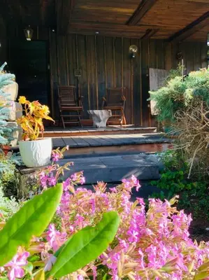 a porch with chairs and flowers in front of a house at Logement avec jardin et vue panoramique MontBlanc in Les Houches