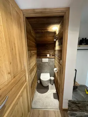 a bathroom with a toilet and wooden walls at Logement avec jardin et vue panoramique MontBlanc in Les Houches