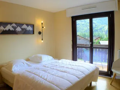 a bedroom with a large bed and a large window at T2 avec mezzanine, balcon et parking à Samoëns - Pour télétravail - FR-1-629-115 in Samoëns