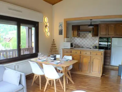 a kitchen with a table and white chairs in a kitchen at T2 avec mezzanine, balcon et parking à Samoëns - Pour télétravail - FR-1-629-115 in Samoëns