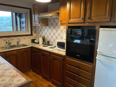 a kitchen with wooden cabinets and a black appliance at T2 avec mezzanine, balcon et parking à Samoëns - Pour télétravail - FR-1-629-115 in Samoëns