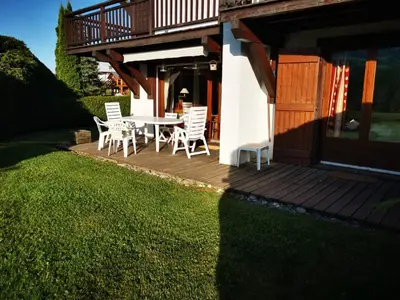 a deck with a table and chairs on a house at MAGNIFIQUE Appart/ 8 pers / 4 ch / Jardin / Vue MB in Megève