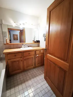 a bathroom with a sink and a wooden door at MAGNIFIQUE Appart/ 8 pers / 4 ch / Jardin / Vue MB in Megève