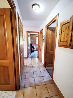 a hallway with wooden doors and a tile floor at MAGNIFIQUE Appart/ 8 pers / 4 ch / Jardin / Vue MB in Megève