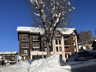 a tree in a pile of snow in front of a building at Studio cosy 4 pers au cœur de la station, proche des pistes et commerces - FR-1-572-268 in Arâches-la-Frasse