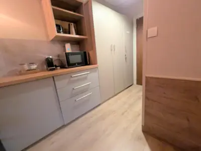 a kitchen with white cabinets and a microwave at Au Petit Bois in Chamonix-Mont-Blanc