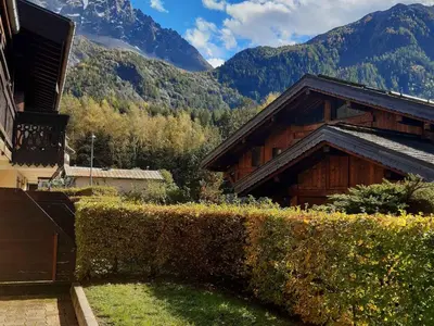 a hedge in front of a building with mountains in the background at T2 rez-de-jardin Chamonix avec parking et vue Mont Blanc - FR-1-517-65 in Chamonix-Mont-Blanc