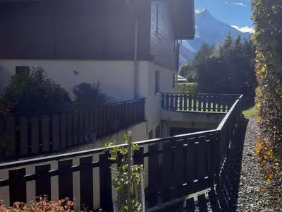 a house with a fence next to a building at T2 rez-de-jardin Chamonix avec parking et vue Mont Blanc - FR-1-517-65 in Chamonix-Mont-Blanc