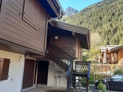 a house with a staircase leading up to a balcony at T2 rez-de-jardin Chamonix avec parking et vue Mont Blanc - FR-1-517-65 in Chamonix-Mont-Blanc