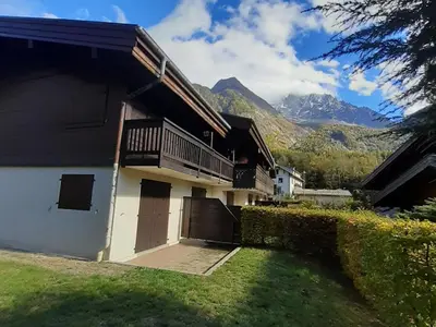 a house with a balcony and mountains in the background at T2 rez-de-jardin Chamonix avec parking et vue Mont Blanc - FR-1-517-65 in Chamonix-Mont-Blanc