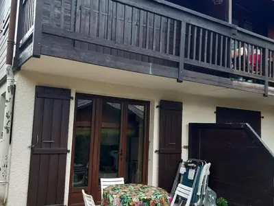a patio with a table and chairs and a balcony at T2 rez-de-jardin Chamonix avec parking et vue Mont Blanc - FR-1-517-65 in Chamonix-Mont-Blanc