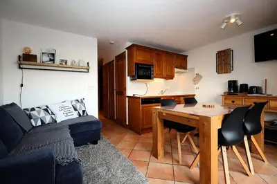 a living room with a couch and a kitchen with a table at Résidence Les Hauts De Chavants - Hauts de chavants Albert 1er n°1 MAE-6254 in Les Houches