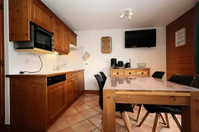 a kitchen with a table with chairs and a television at Résidence Les Hauts De Chavants - Hauts de chavants Albert 1er n°1 MAE-6254 in Les Houches