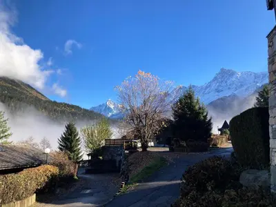 a road in a village with mountains in the background at Résidence Les Hauts De Chavants - Hauts de chavants Albert 1er n°1 MAE-6254 in Les Houches