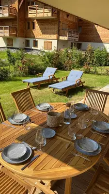 a wooden table with plates and wine glasses on it at Mont d'arbois, 3 chambres avec terrasses et sauna dans la résidence in Megève