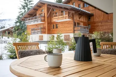 a wooden table with two coffee cups on top of it at Mont d'arbois, 3 chambres avec terrasses et sauna dans la résidence in Megève
