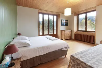 a bedroom with a large bed and two windows at Saint Éloi - Panoramic view - Mont Joly - Central in Saint-Gervais-les-Bains