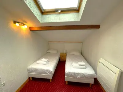 two beds in a small room with a skylight at Duplex centre Chamonix pour 6 avec parking et wifi - FR-1-343-240 in Chamonix-Mont-Blanc