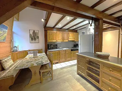 a kitchen with wooden cabinets and a table and a refrigerator at Duplex centre Chamonix pour 6 avec parking et wifi - FR-1-343-240 in Chamonix-Mont-Blanc