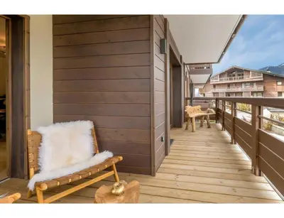 a balcony with a bench and a chair on it at Luxurious 4-room with pool, gym, spa and parking in Megève