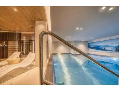 a large swimming pool in a building with a swimming pool at Luxurious 4-room with pool, gym, spa and parking in Megève