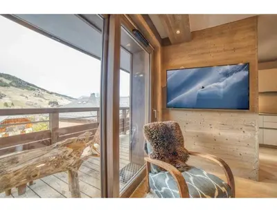 a room with a chair and a tv on a wall at Luxurious 4-room with pool, gym, spa and parking in Megève