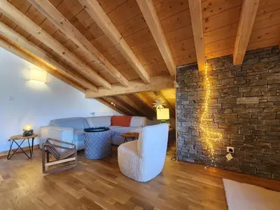 a living room with a couch and a stone wall at Atypique T4 lumineux avec vue panoramique, 3 Ch, 6-8 pers, WIFI, parking couvert - FR-1-629-112 in Samoëns
