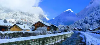 a village with snow covered mountains in the background at LE GRAND TETRAS in Samoëns