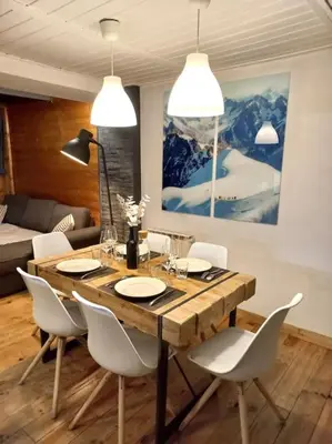 a dining room with a wooden table and white chairs at Bel appartement familial et cosy in Saint-Gervais-les-Bains