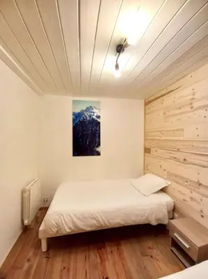 a bedroom with a white bed and a wooden wall at Bel appartement familial et cosy in Saint-Gervais-les-Bains
