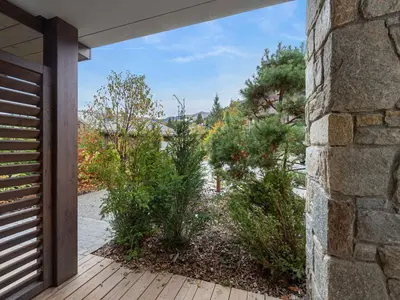 an open door to a garden with bushes at Appartement cosy à Rochebrune, piscine et parking - FR-1-569-58 in Megève