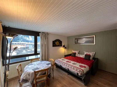 a bedroom with a bed and a table and a window at STUDIO DENT DU CAIMAN, CHAMONIX hyper CENTRE, PARKING, VUE MONT BLANC in Chamonix-Mont-Blanc