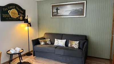 a living room with a couch and a picture on the wall at STUDIO DENT DU CAIMAN, CHAMONIX hyper CENTRE, PARKING, VUE MONT BLANC in Chamonix-Mont-Blanc