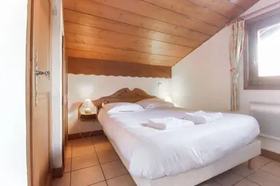 a bedroom with a white bed with a wooden ceiling at Le Goûter - Ski-in ski-out - Indoor Pool in Les Houches