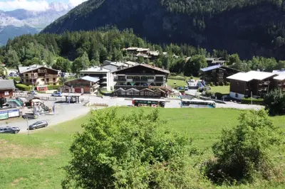 a small town in the mountains with a green field at Le Goûter - Ski-in ski-out - Indoor Pool in Les Houches