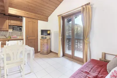 a kitchen and living room with a table and a window at Le Goûter - Ski-in ski-out - Indoor Pool in Les Houches