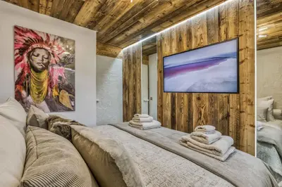 a room with a large bed with a large painting on the wall at Le petit cœur de Megève -Mont770- in Megève