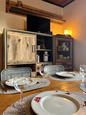a wooden table with plates and wine glasses on it at Le Chaney - T2 dans chalet - Massif du Mont-Blanc in Chamonix-Mont-Blanc