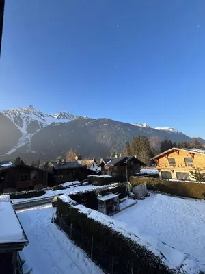 a village covered in snow with mountains in the background at Le Chaney - T2 dans chalet - Massif du Mont-Blanc in Chamonix-Mont-Blanc
