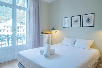 a white bedroom with a large bed and a window at Majestic Alpin - A luxurious apartment with a nordic feel in Chamonix-Mont-Blanc