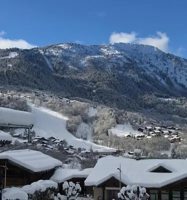 a village covered in snow with a mountain in the background at Appartement 2pieces Hyper Centre Les Houches, proche Chamonix in Les Houches