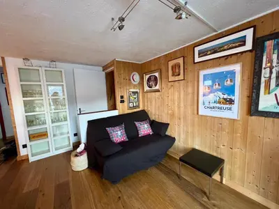a living room with a black couch and wooden walls at Appartement 2pieces Hyper Centre Les Houches, proche Chamonix in Les Houches