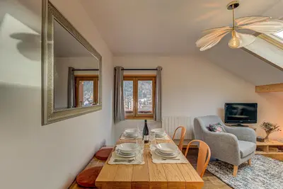 a living room with a wooden table and a chair at Apartment Rebats - Alpes Travel - Central Chamonix in Chamonix-Mont-Blanc