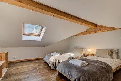 two beds in a attic room with a window at Apartment Rebats - Alpes Travel - Central Chamonix in Chamonix-Mont-Blanc