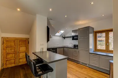 a kitchen with stainless steel appliances and wooden floors at Apartment Rebats - Alpes Travel - Central Chamonix in Chamonix-Mont-Blanc
